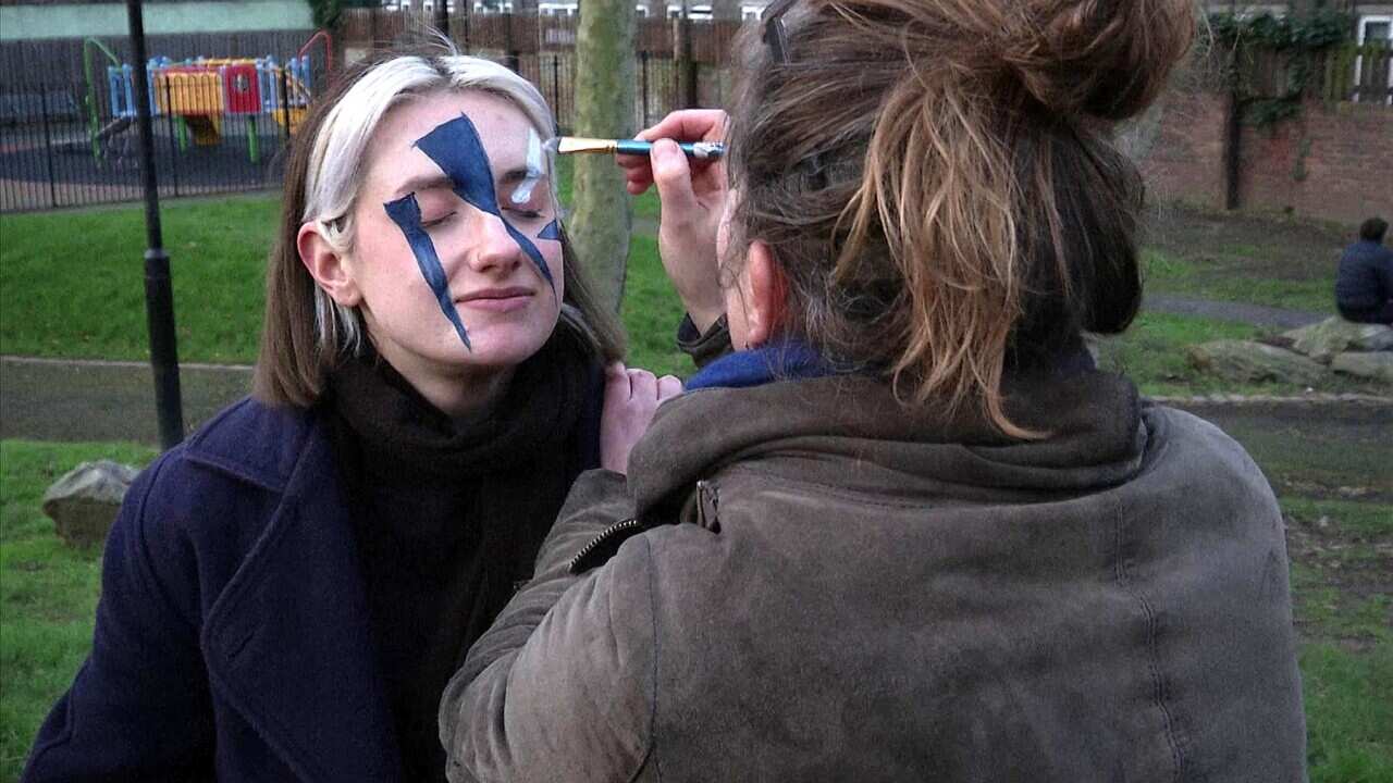 Members of the Dazzle Club work on their painted faces
