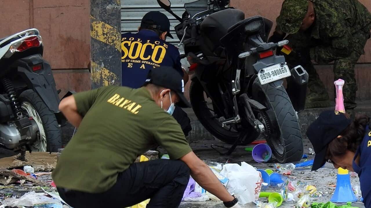 Police officers investigate the site of an explosion outside a shopping mall in Cotabato City.