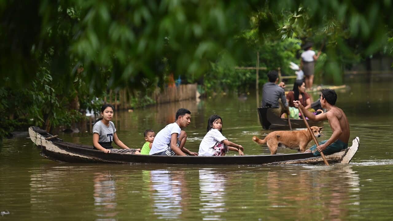 Residents ride in a boat through floodwaters in Bago.