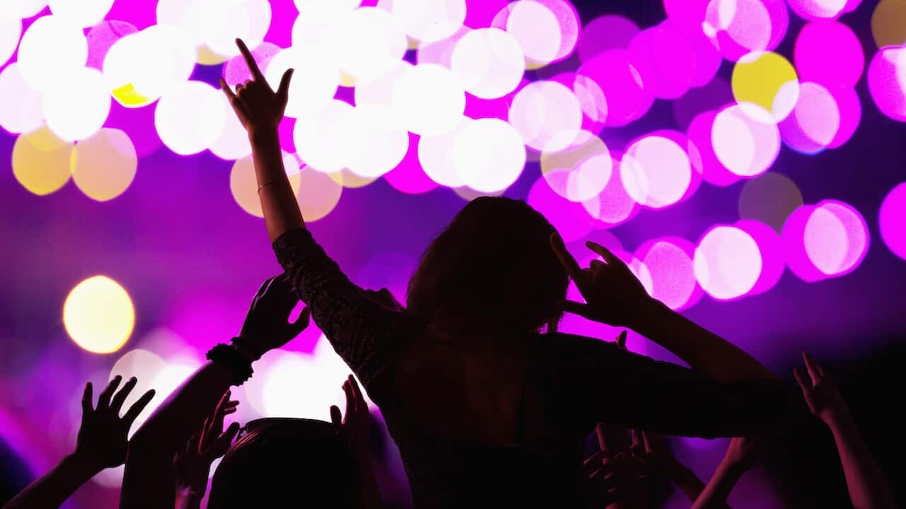 Audience watching a rock show, rear view, stage lights