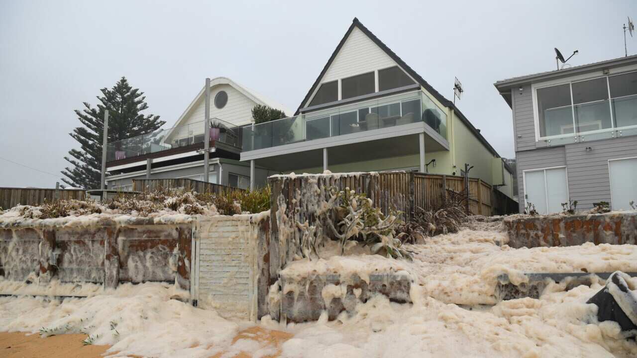 Sea foam approaching beachfront houses after heavy rain and storms at Collaroy in Sydney's Northern Beaches