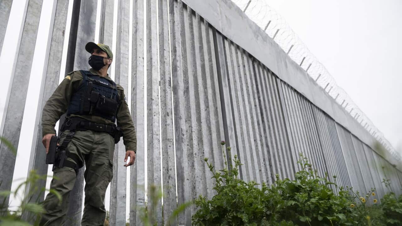 A policeman patrols a steel wall at Evros river, near the village of Poros, at the Greece -Turkey border on May 21, 2021