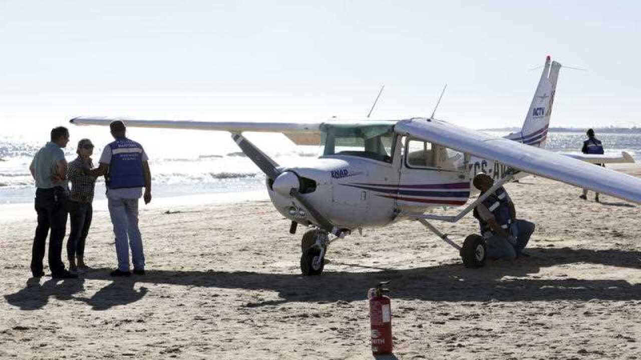 Portuguese coastguard officers check a small plane after an emergency landing at Sao Joao beach in Costa da Caparica, outside Lisbon, Wednesday, Aug. 2 2017.