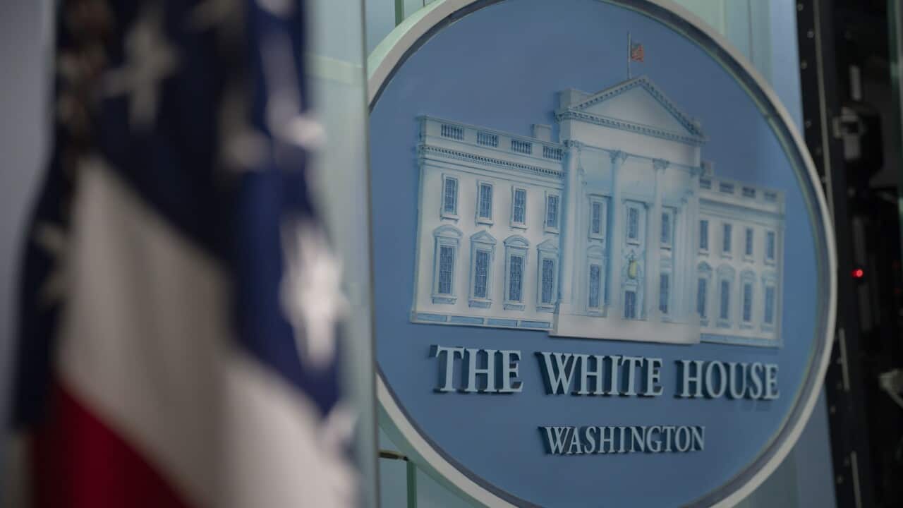 El logotipo de la Casa Blanca junto a una bandera de los Estados Unidos.