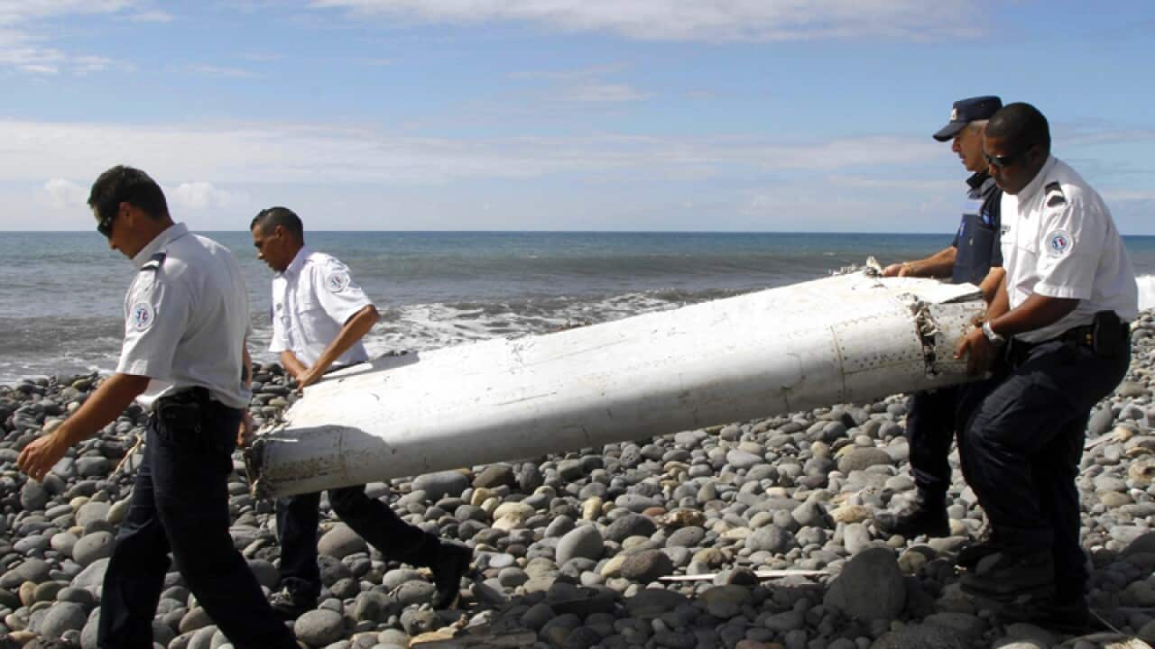 Officers carry pieces of debris confirmed to be from MH370