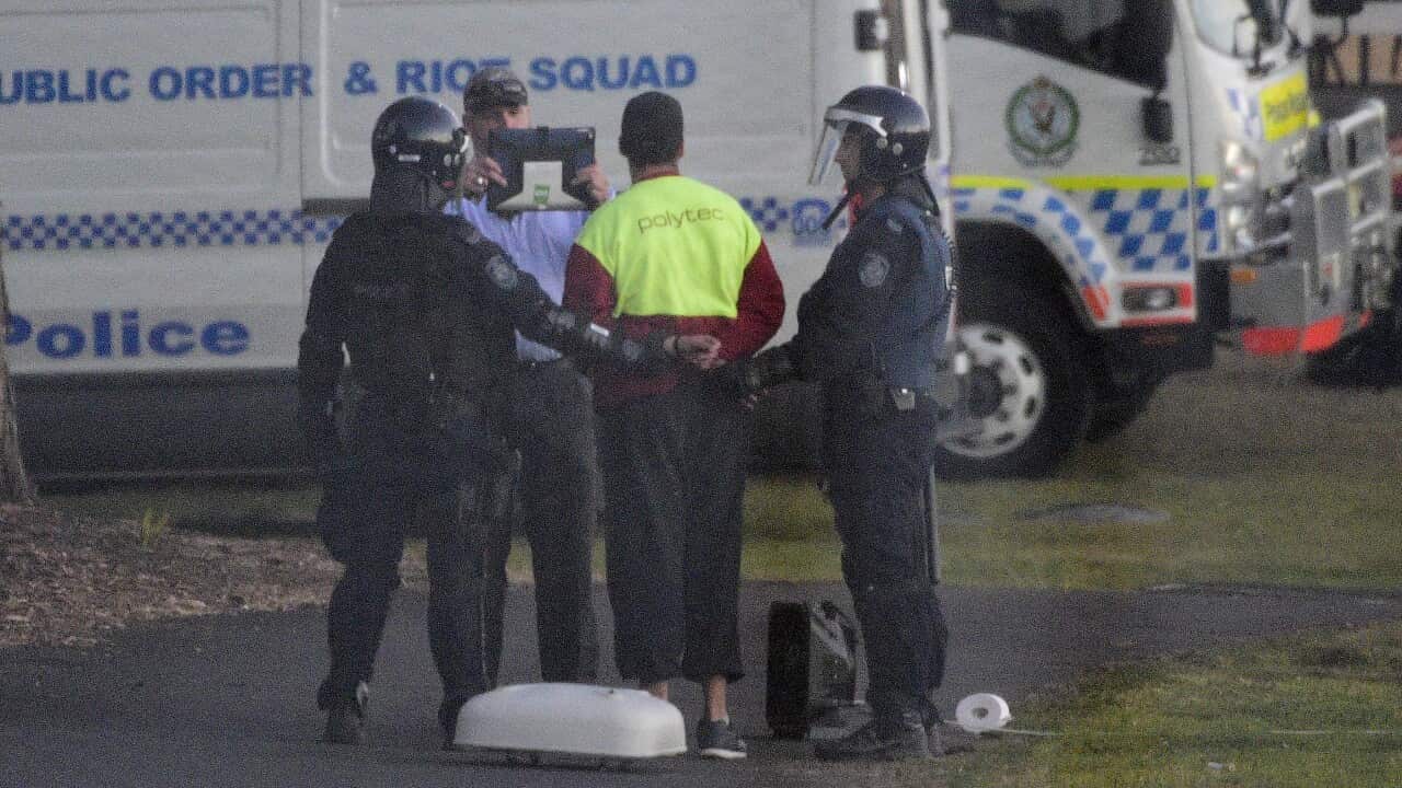 Riot police lead a detainee away in handcuffs during a riot at the Frank Baxter Juvenile Justice Centre.
