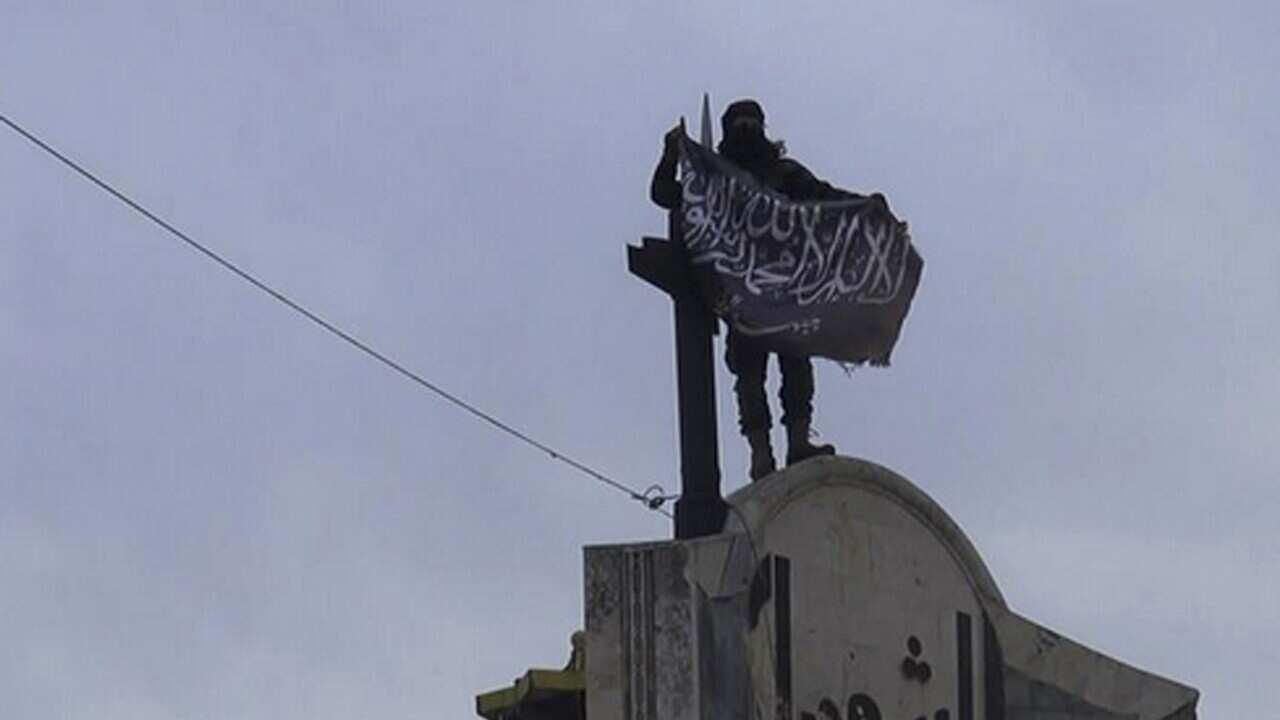 File photo of a fighter from Syria's al-Qaida-linked Nusra Front holds his group flag in Idlib province, north Syria.