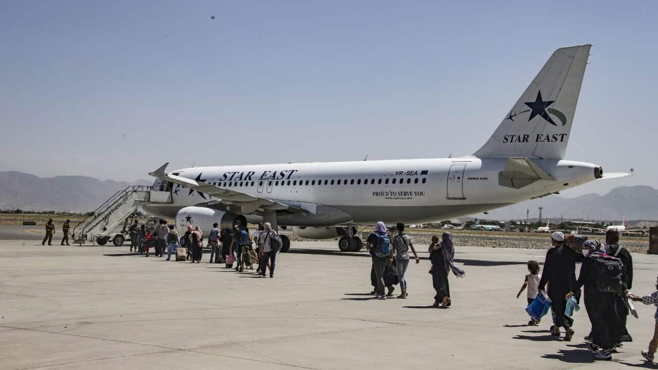 A Marine assigned to the 24th Marine Expeditionary Unit escort evacuees to an aircraft at Hamid Karzai International Airport on 25 August 2021.