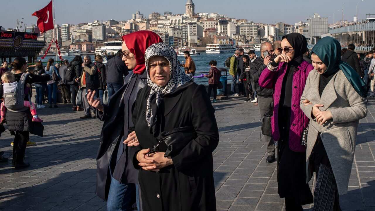 People at Eminonu Square, with Galata Tower seen in the background, on a sunny day in Istanbul, Turkey.