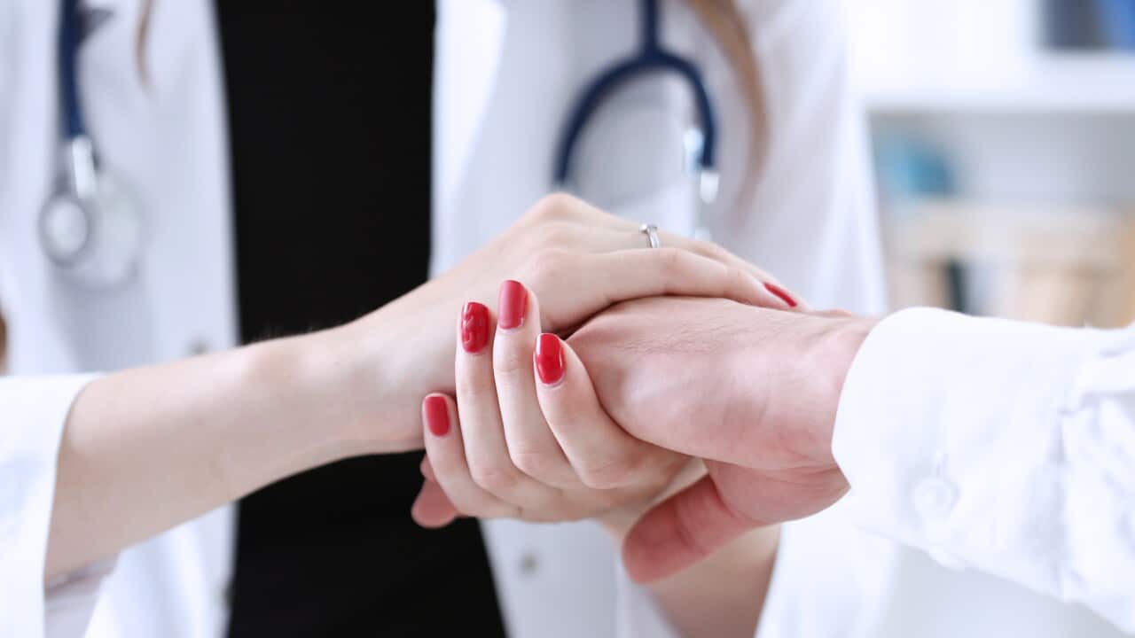 Friendly female doctor hold male patient hand in office.