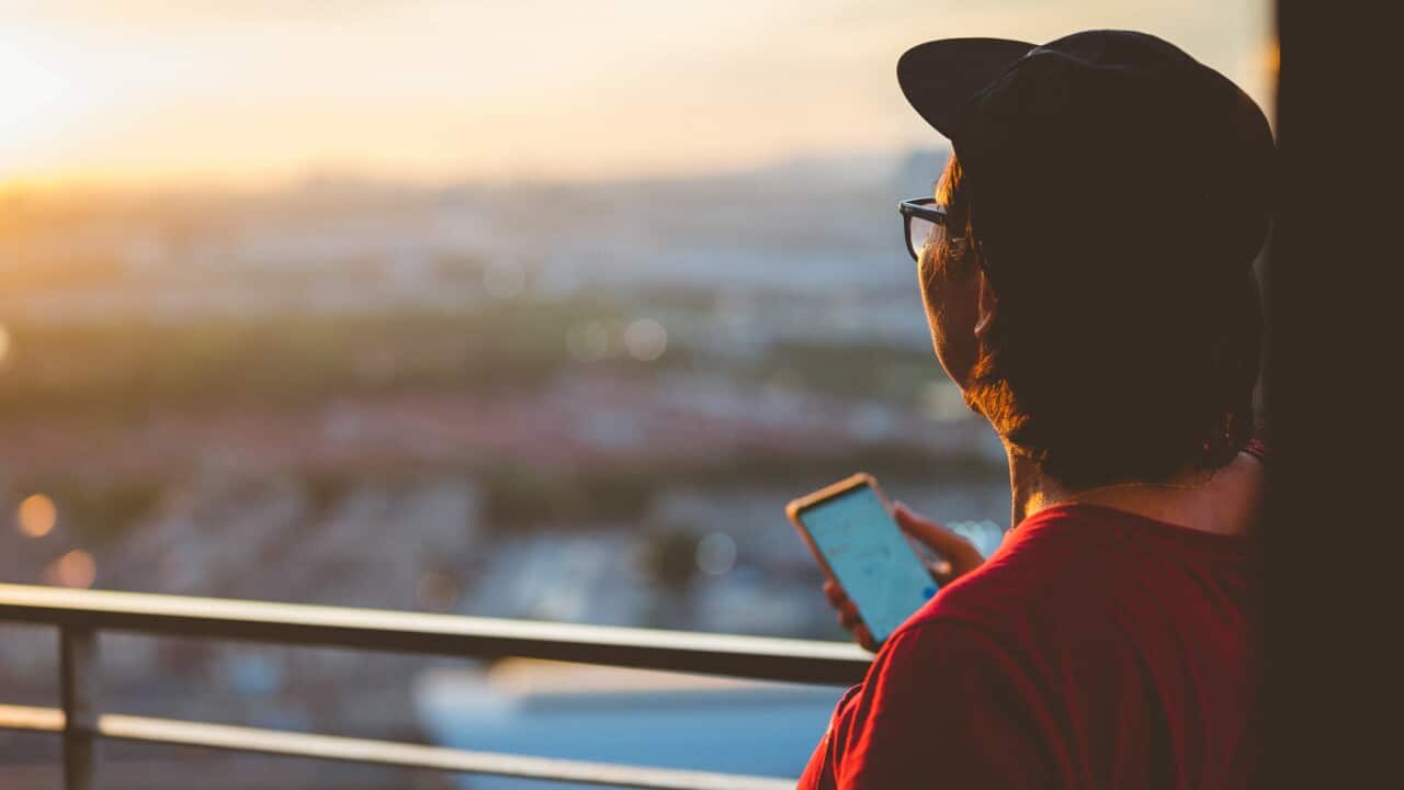 Young man in red shirt looking out at sunset
