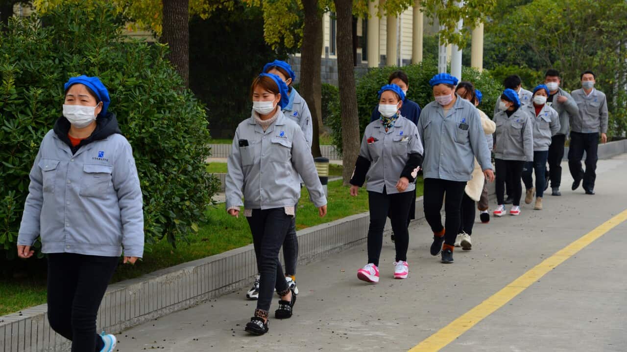 Masked female Chinese workers walk alone and separately for prevention of the novel coronavirus