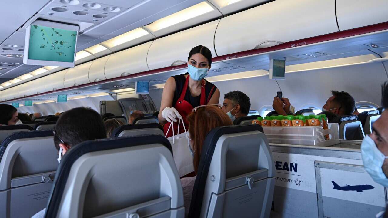 cabin crew member in protective gear serving passengers