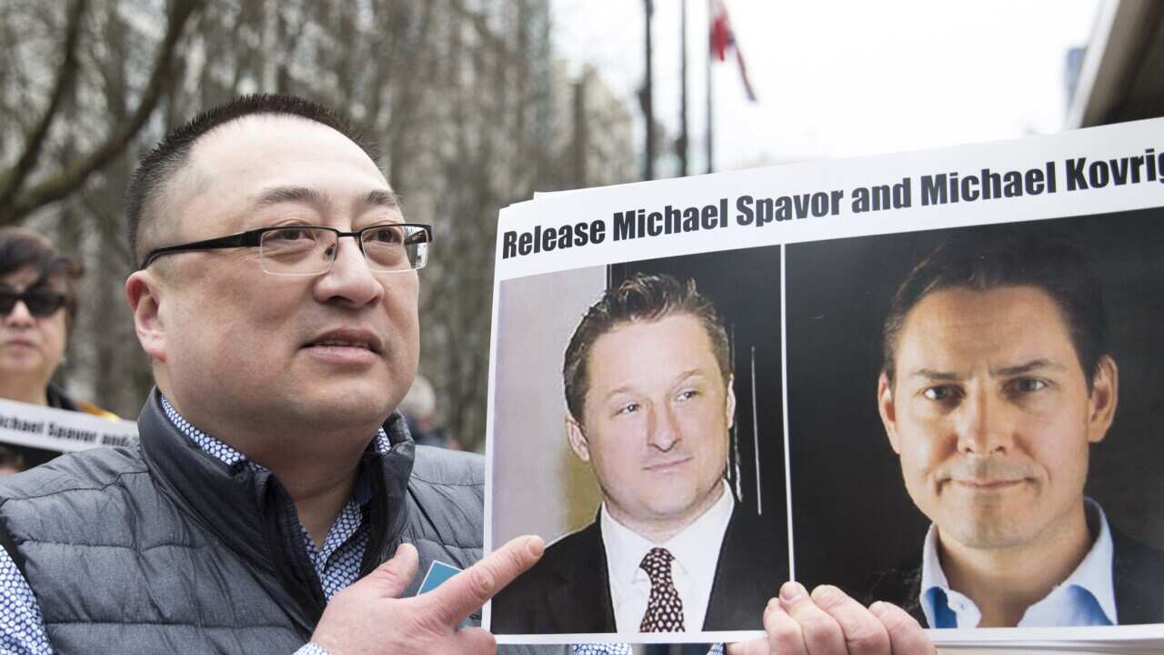 Louis Huang of Vancouver Freedom and Democracy for China holds photos of Canadians Michael Spavor and Michael Kovrig.