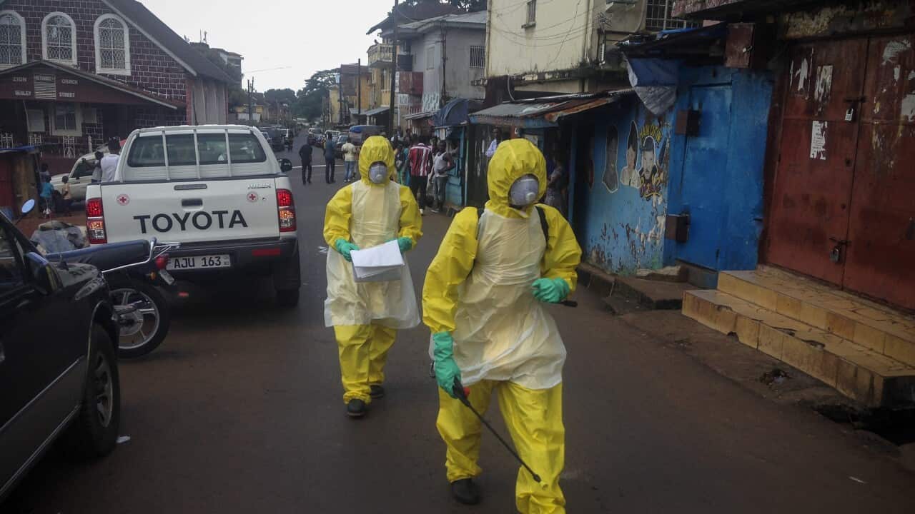 Sierra Leone health workers walk to pick up a 4-month old baby victim that died of Ebola
