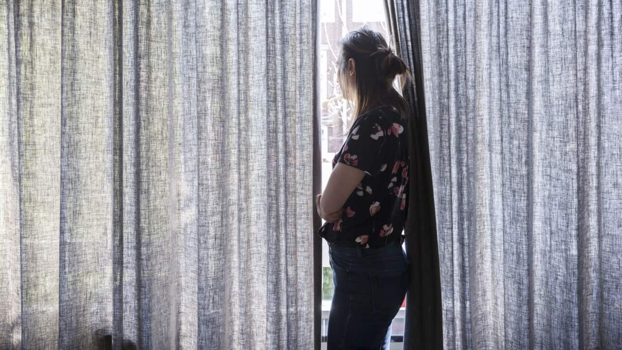 Woman looking outside the window during quarantaine.