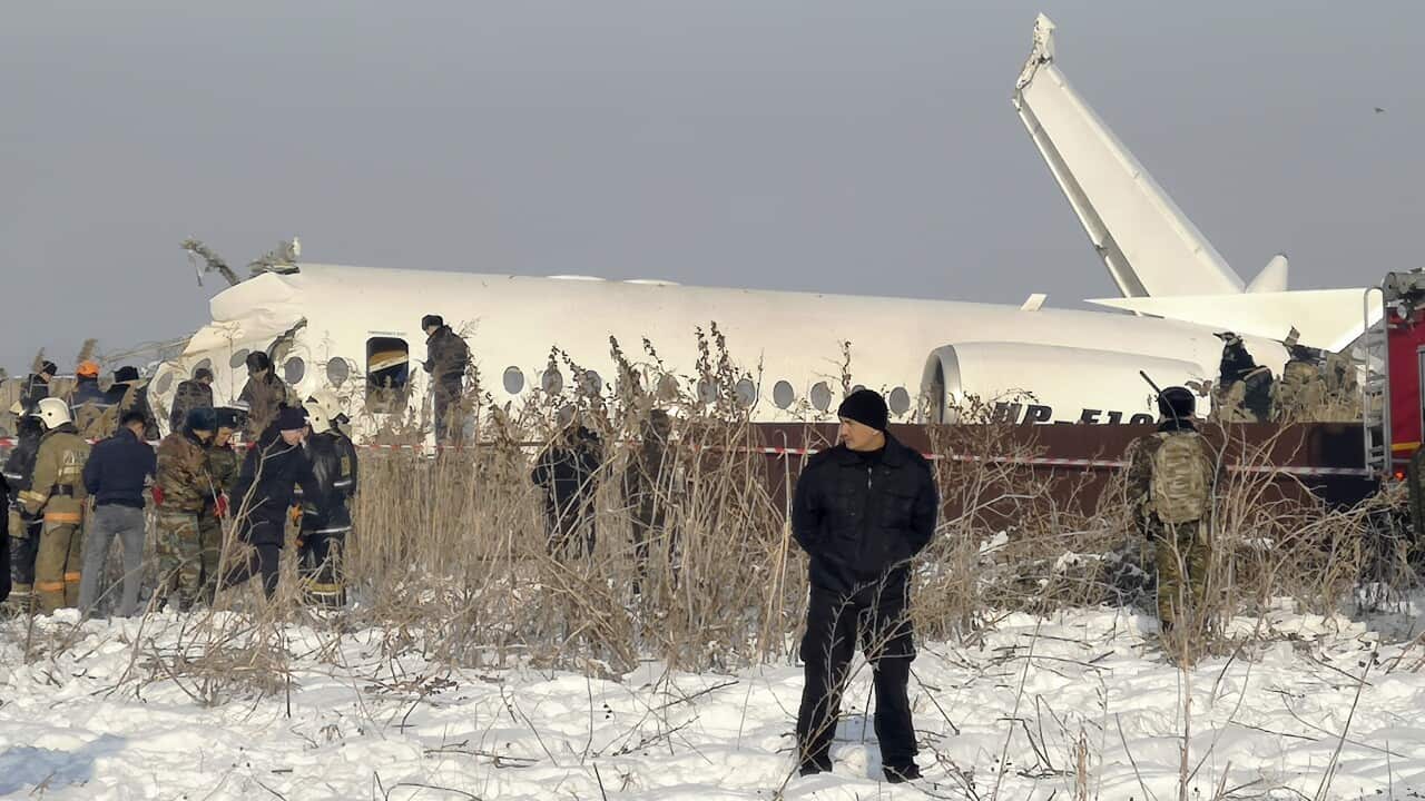 Police stand guard as rescuers work on the side of a plane crash near Almaty International Airport, outside Almaty, Kazakhstan.