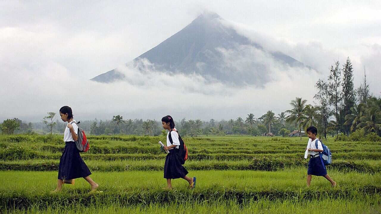 School children cross a field in the Philippines