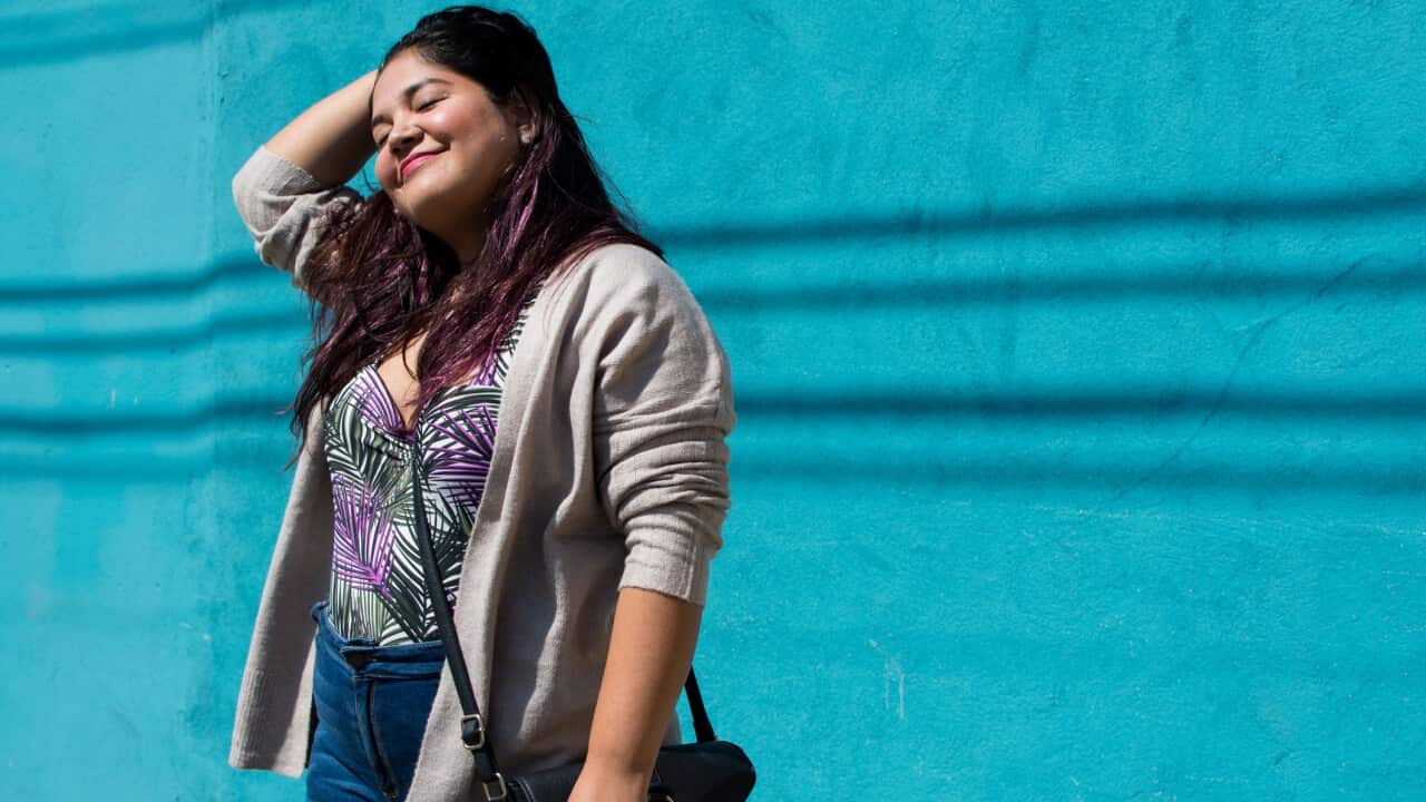 Portrait of a beautiful latina woman standing in front of a blue wall.
