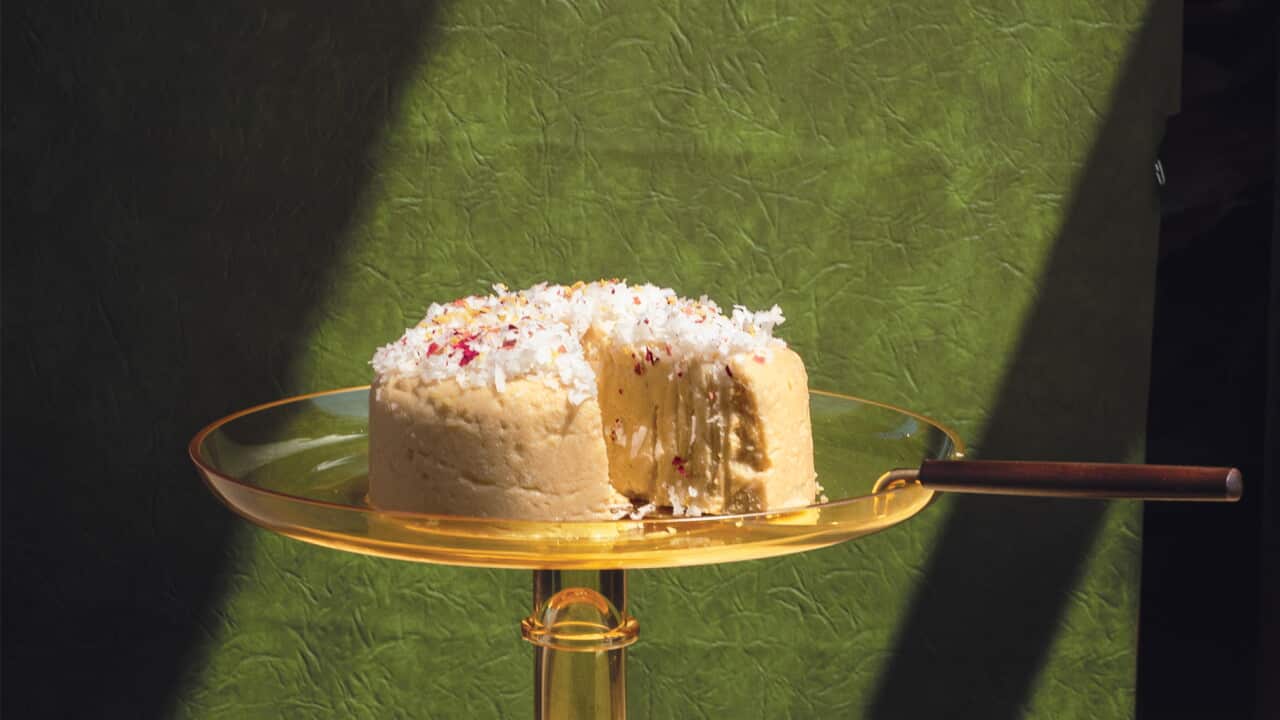A cake-shaped pudding with a slice removed sits on a footed, yellow glass cake stand.