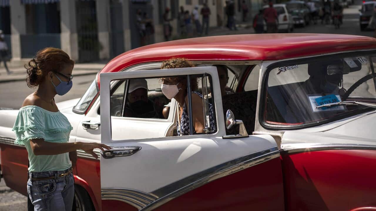 People wearing masks as a precaution against coronavirus exit a taxi in Havana, Cuba