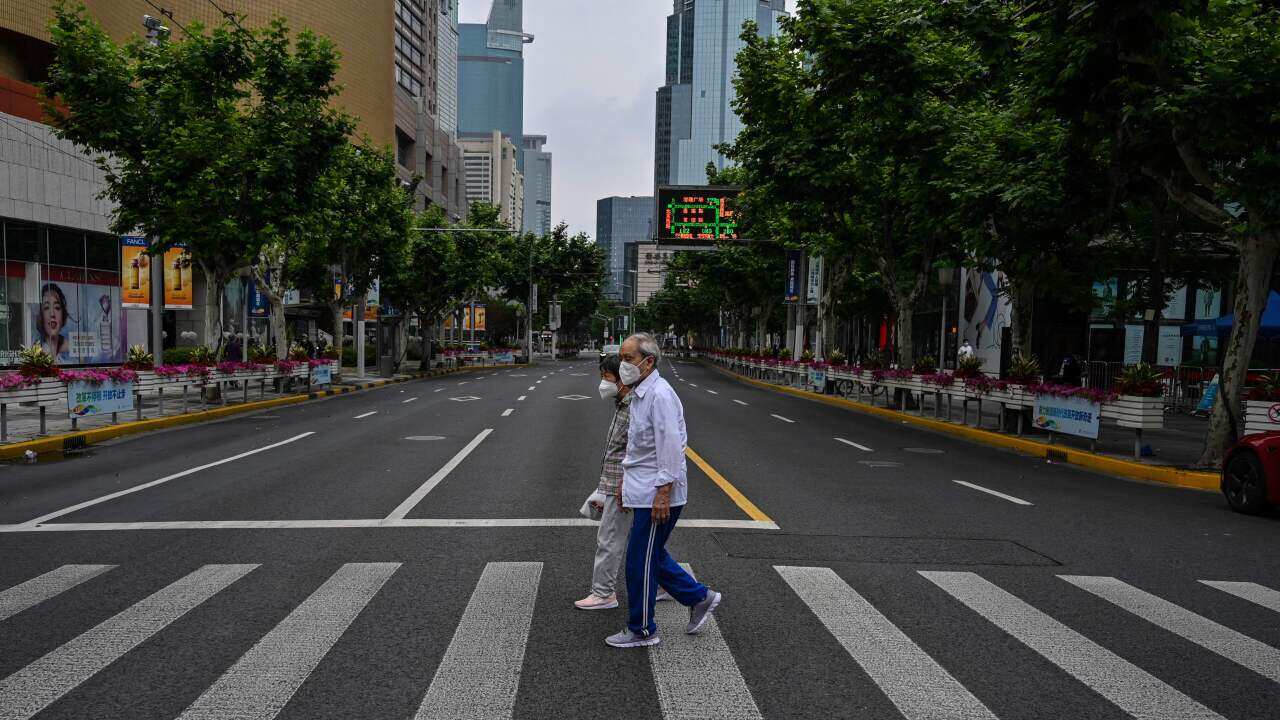 People cross a deserted street in the Jing'an district of Shanghai