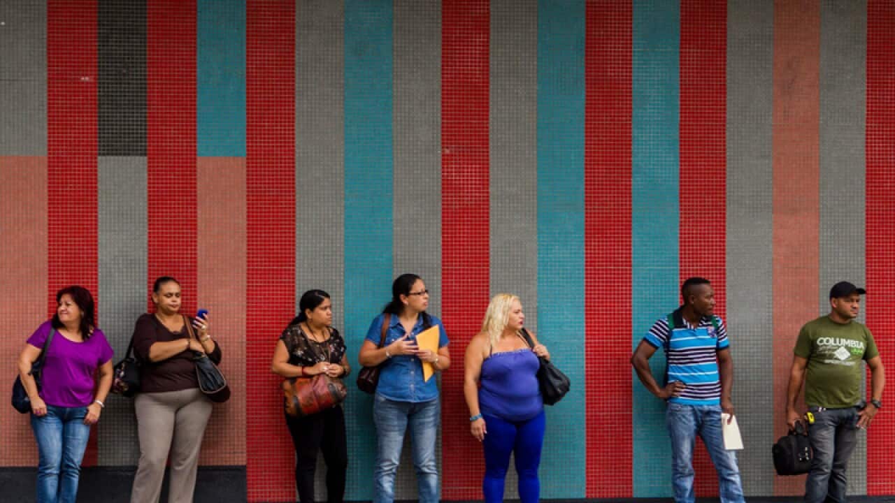 A group of people wait for public transport amid a blackout in Caracas