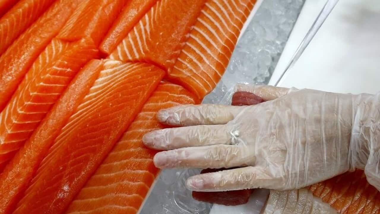 A woman cuts salmon to be sold at a fish store