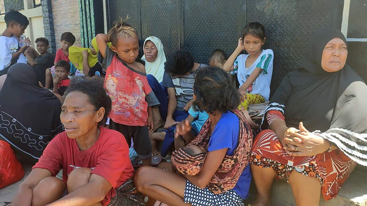 People wait outside their house following an earthquake in Maumere, Indonesia.