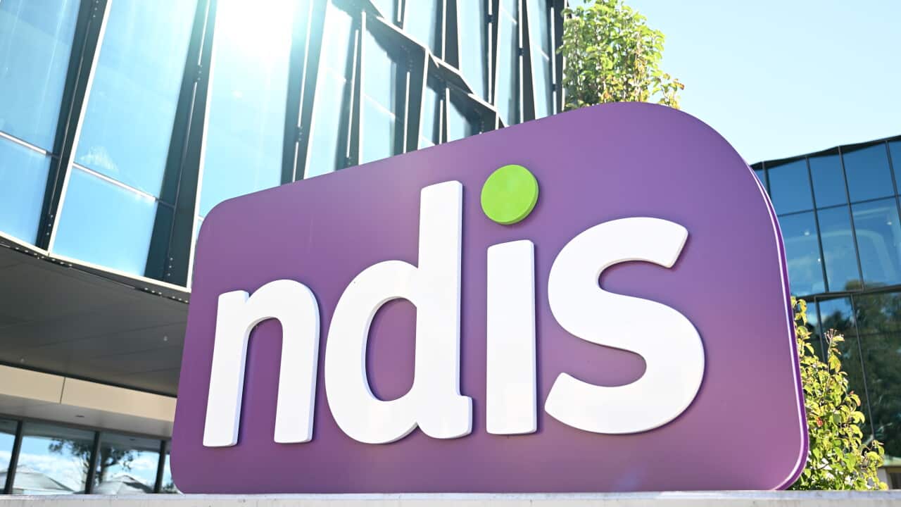 A large purple sign outside a glass building that reads 'NDIS' in white lettering.