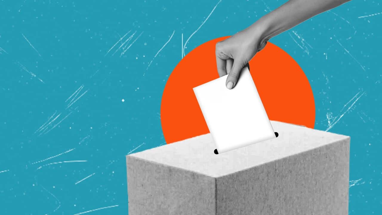 A person casting a ballot into a gray box against a vibrant blue background.