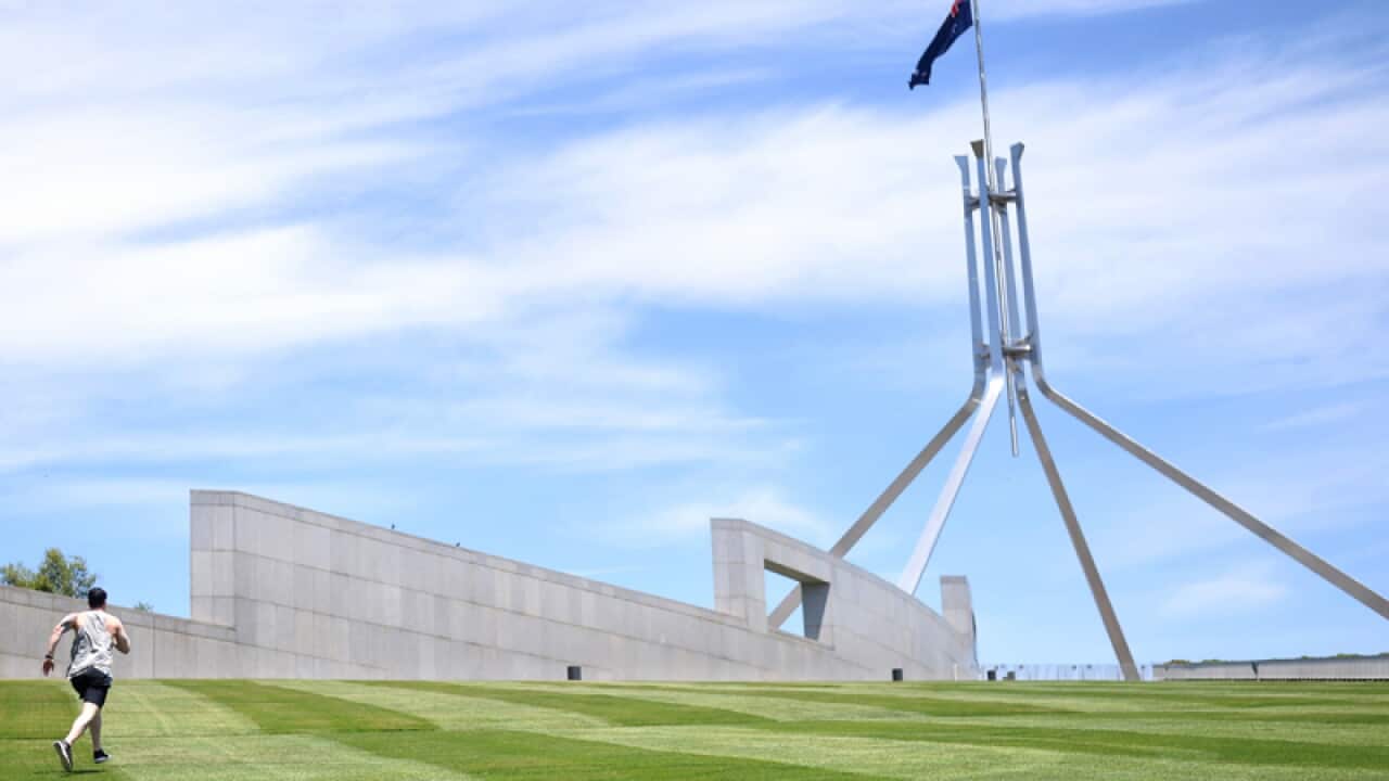 A man runs up the lawns outside Parliament House