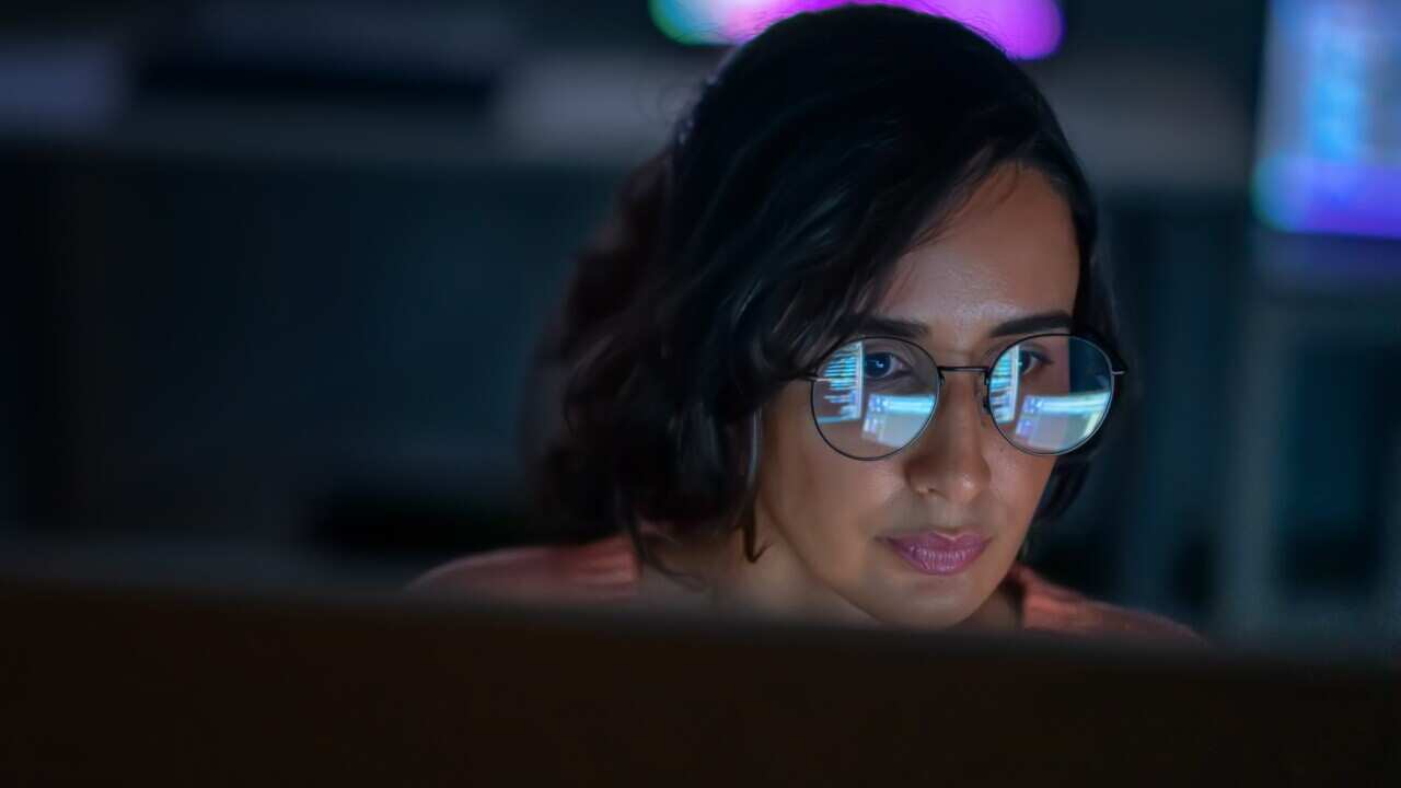 A woman working on a computer while seated at a desk.