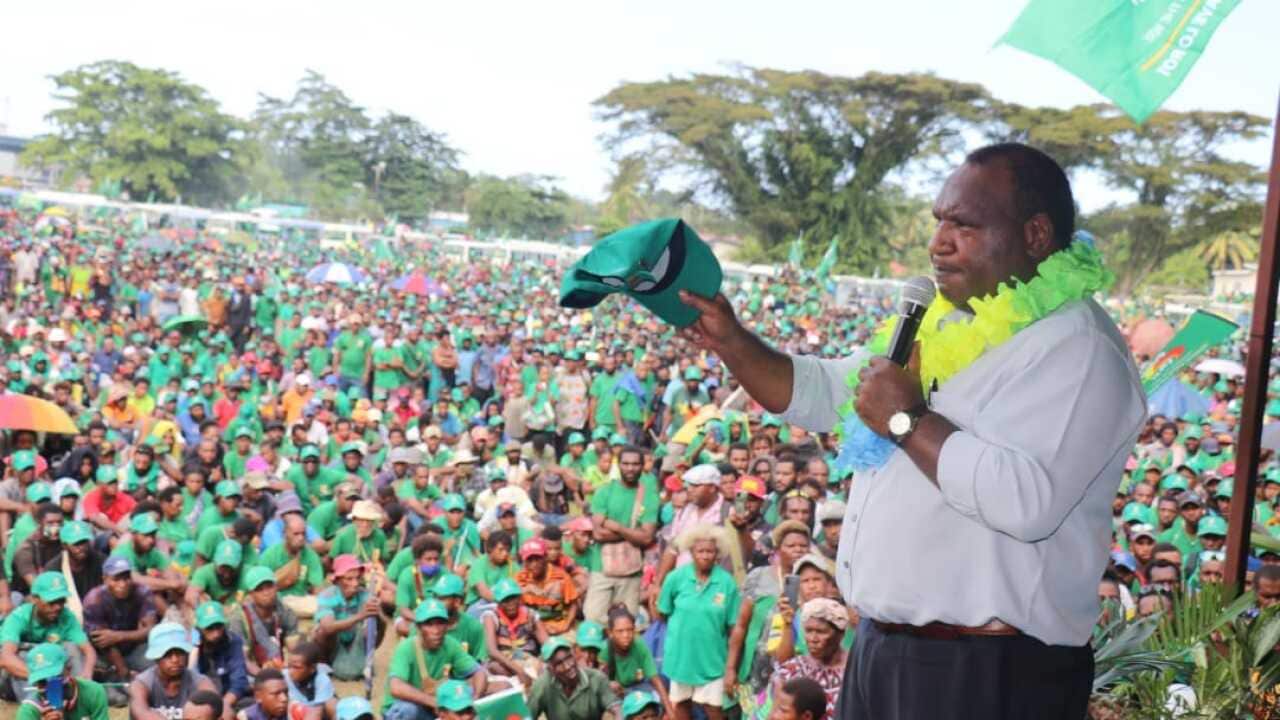 Papua New Guinea's Prime Minister, James Marape, stands on stage with a microphone, addressing his supporters.
