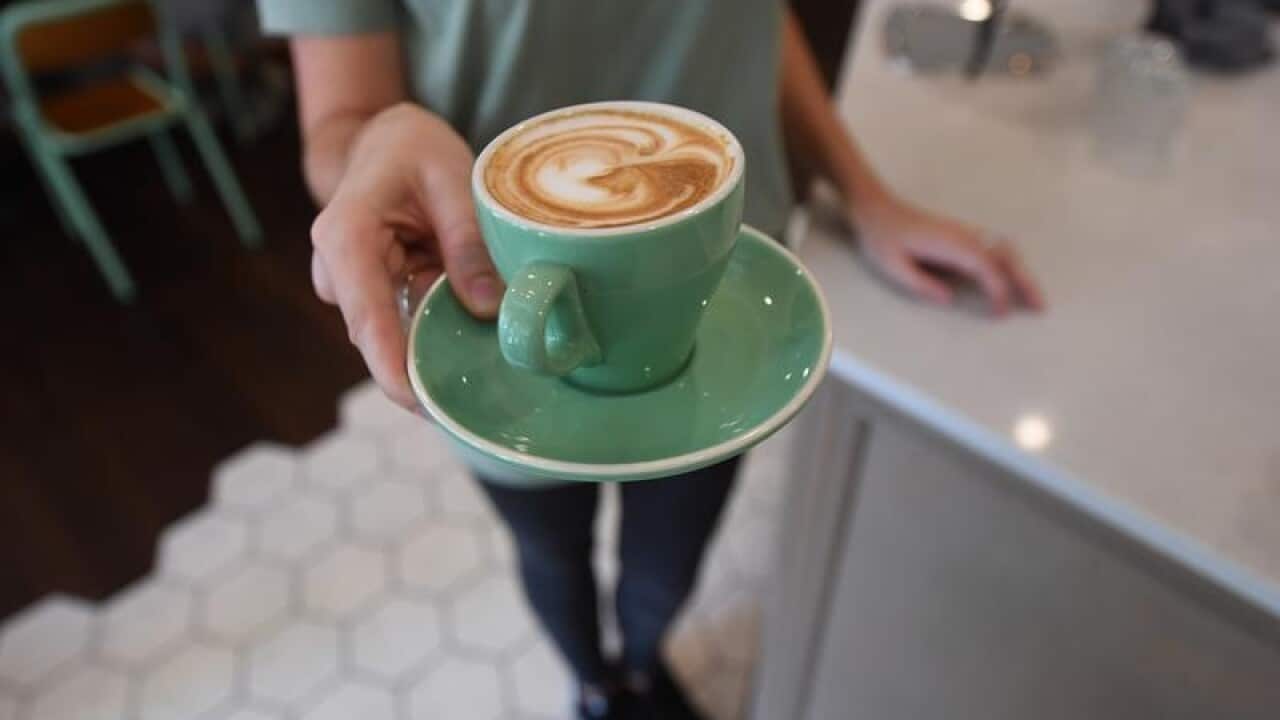 A waitress is seen holding a coffee at a cafe