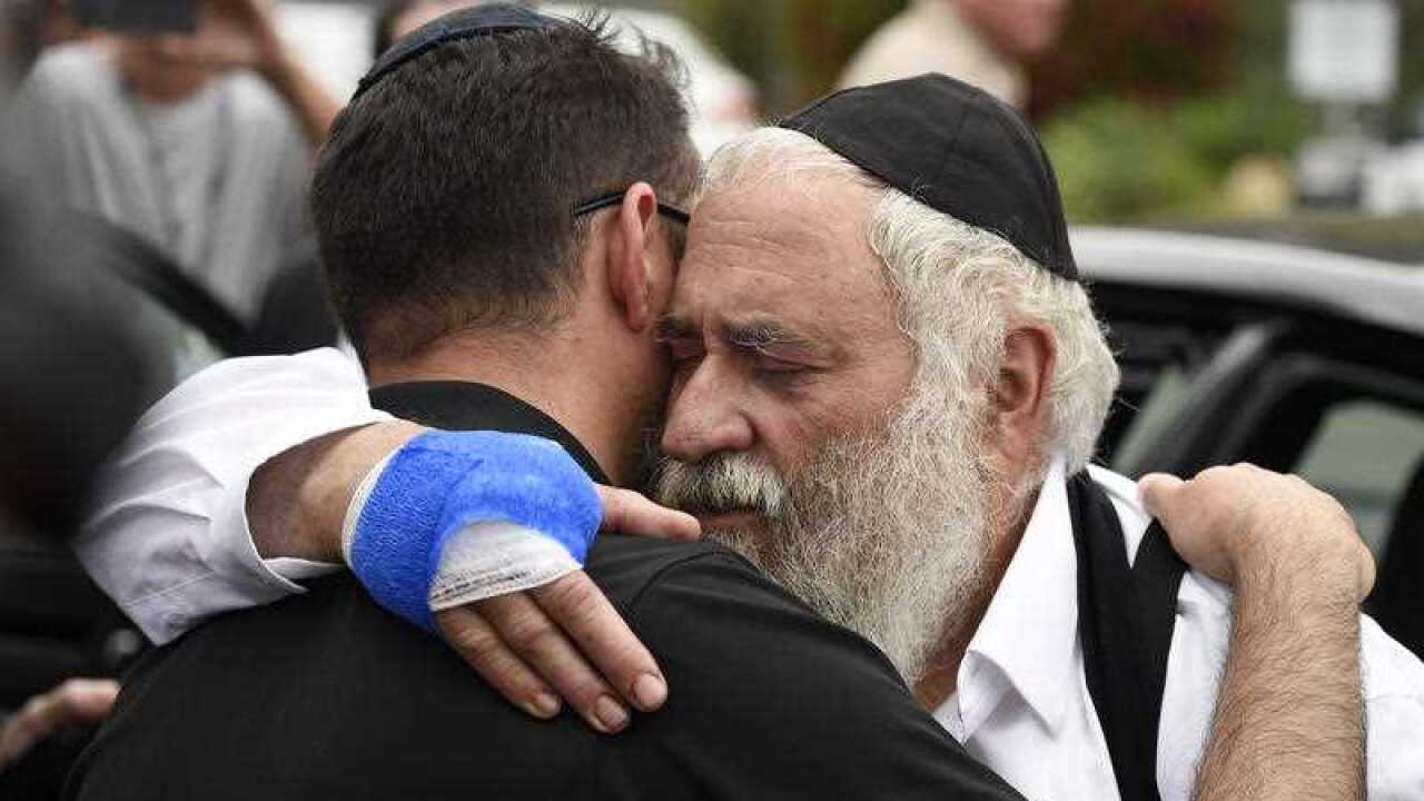 Rabbi Yisroel Goldstein (right) comforts a worshipper outside the Chabad of Poway synagogue in California following a mid-worship shooting.,