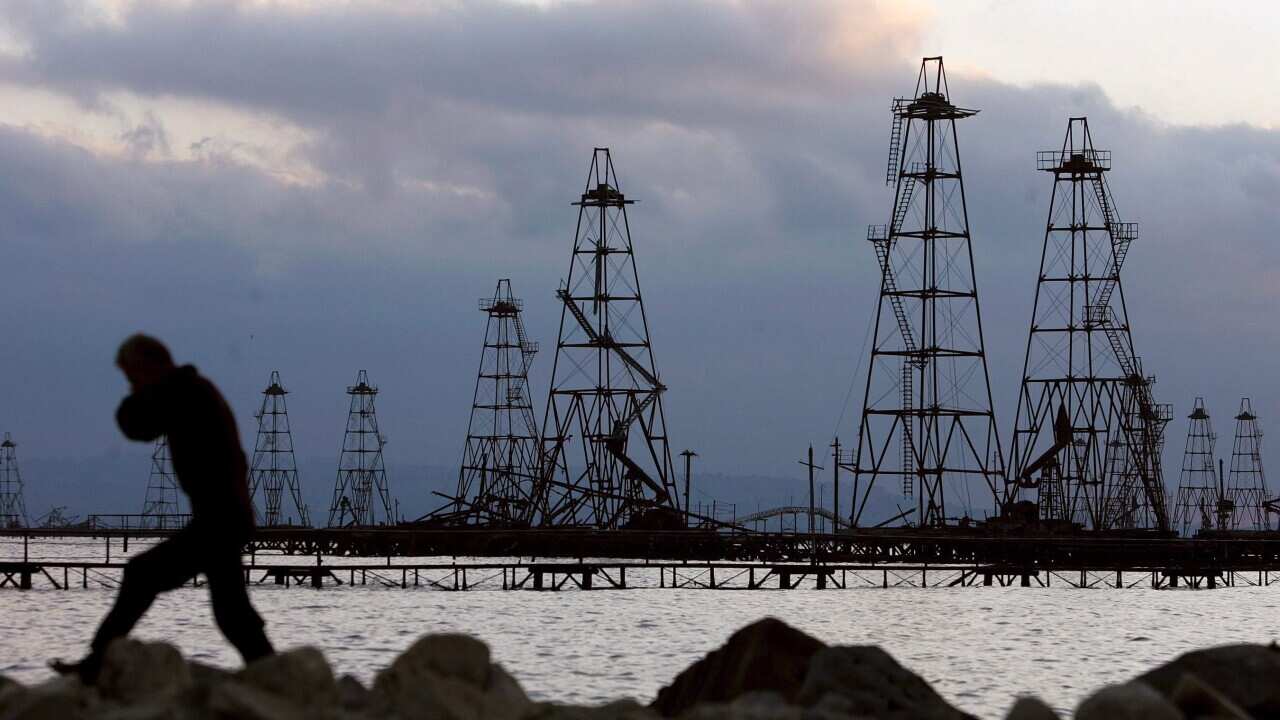 A file photo dated 07 October 2005 showing a worker walking in front of the oil derricks on the Caspian Sea near Baku, Azerbaijan. (EPA/SERGEI ILNITSKY)