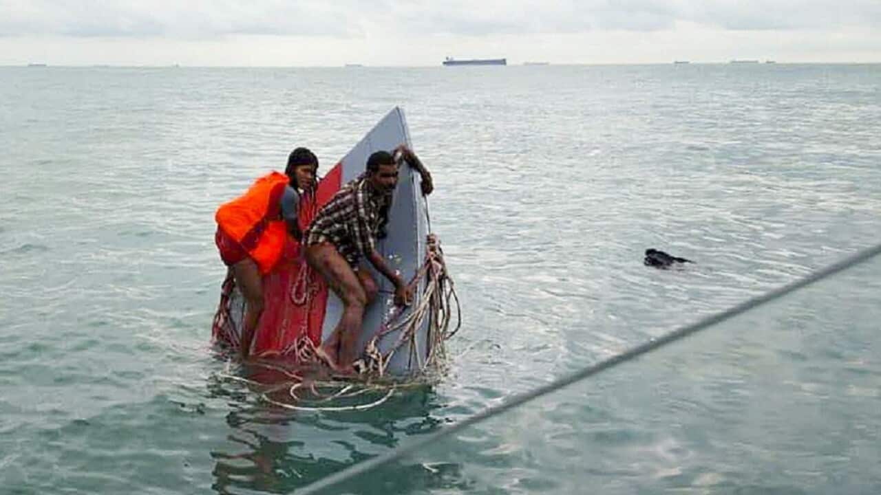 A photo from the Malaysian Maritime Enforcement Agency shows two of the victims stuck on the ship.