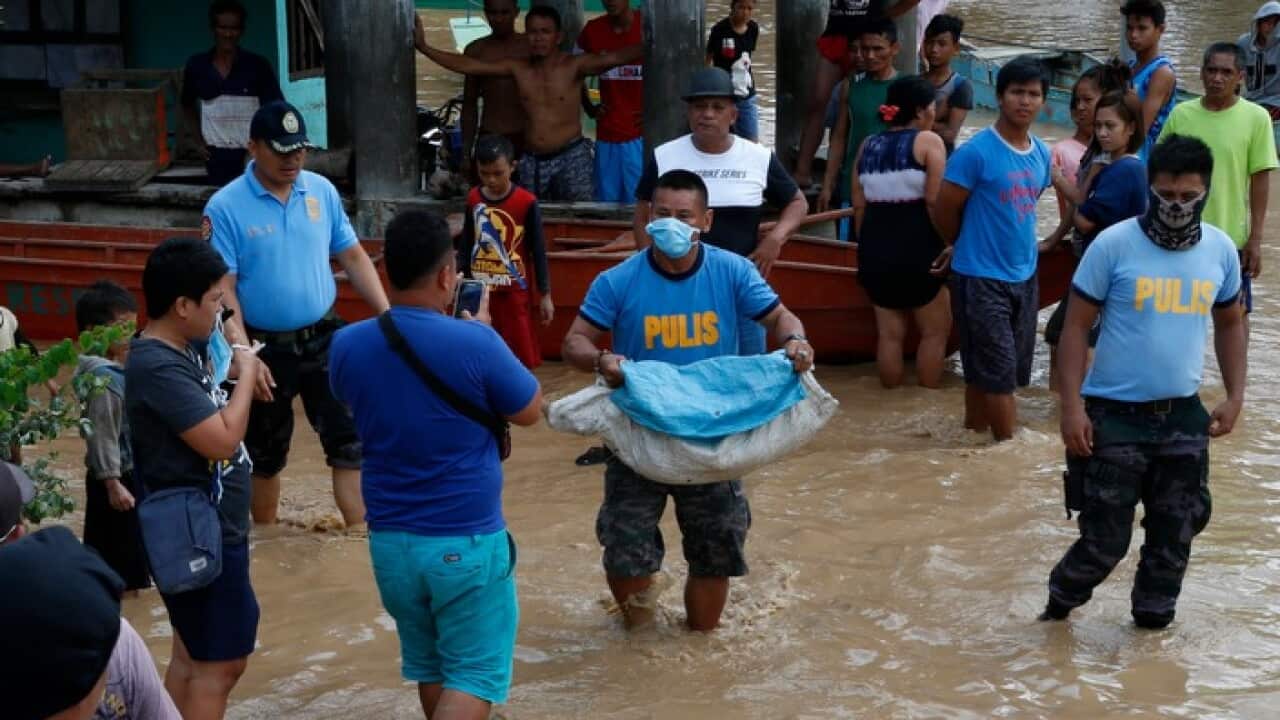 A Filipino policeman carries a body of a victim on floodwater in flood hit town of Salvador, Lanao del Norte province, Philippines, 23 December 2017.