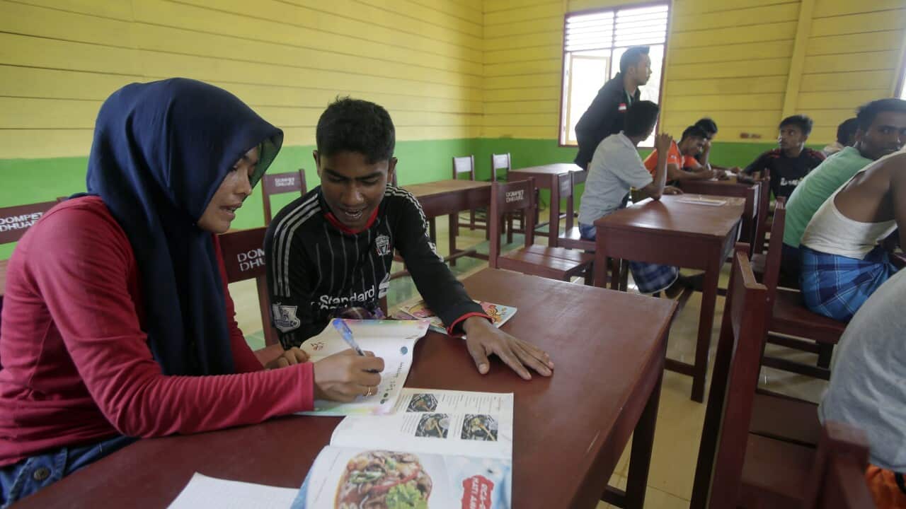A picture shows Nurul (L) an Indonesian volunteer from Save the Children, teaching Bahasa Indonesia to a Rohingya migrant man. (EPA)