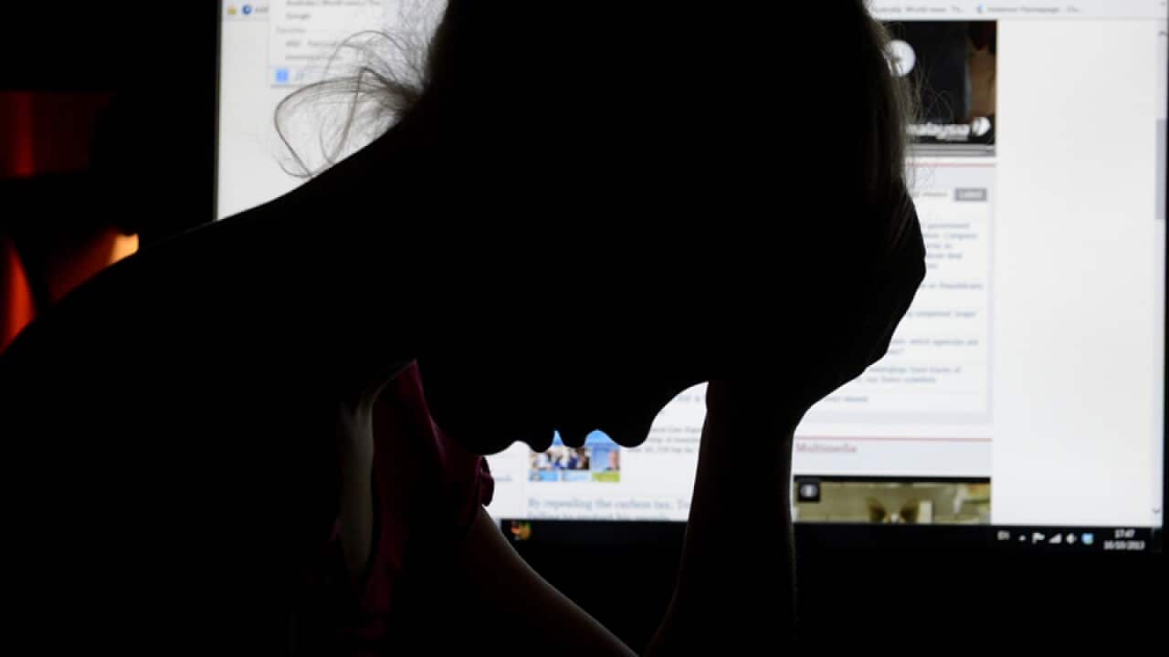An upset young girl in front of a personal computer.