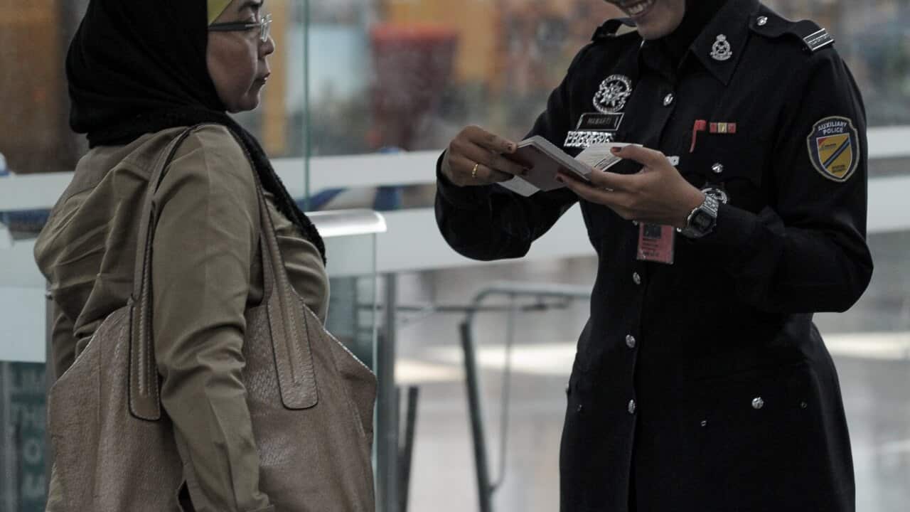 A Malaysian policewoman checks the passport of a passsenger Kuala Lumpur International Airport getty.jpg