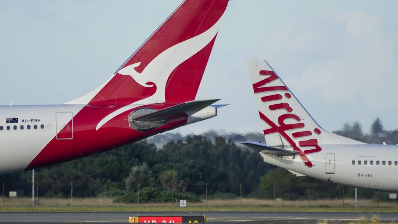 Qantas and Virgin passenger jets pass as they taxi at Sydney Airport.