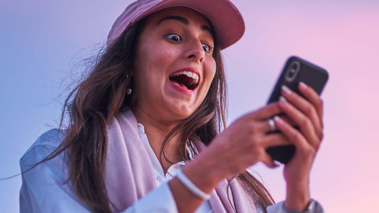 A woman with an excited facial expression using her mobile phone.