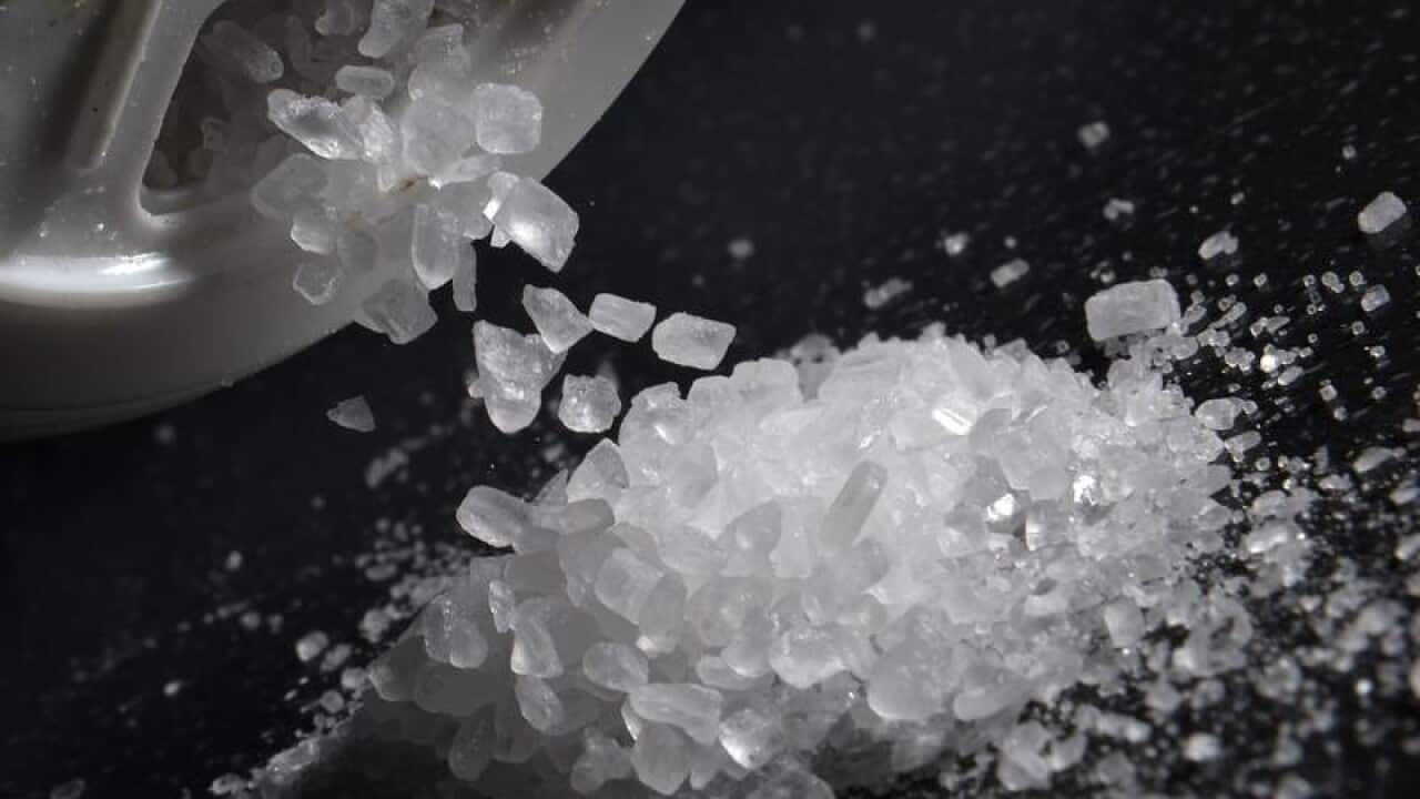 Sea salt is poured from a salt shaker.