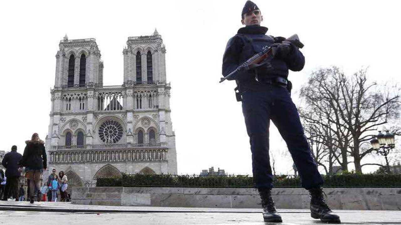 A French Police officer stands guards as worshipers arrive for the Easter mass at Notre Dame Cathedral, in Paris. Police officials say Wednesday Sept. 7, 2016