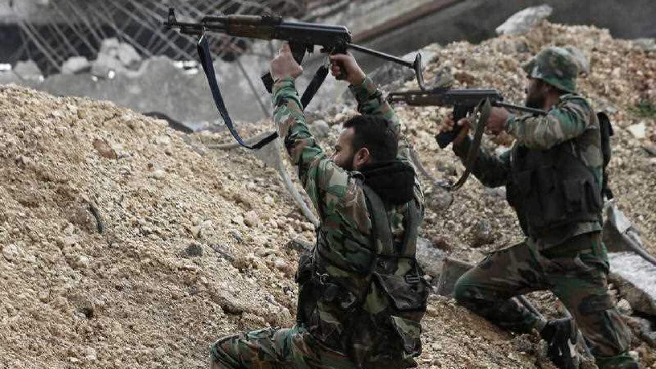 Syrian army soldiers fire their weapons during a battle with rebel fighters at the Ramouseh front line, east of Aleppo, Syria