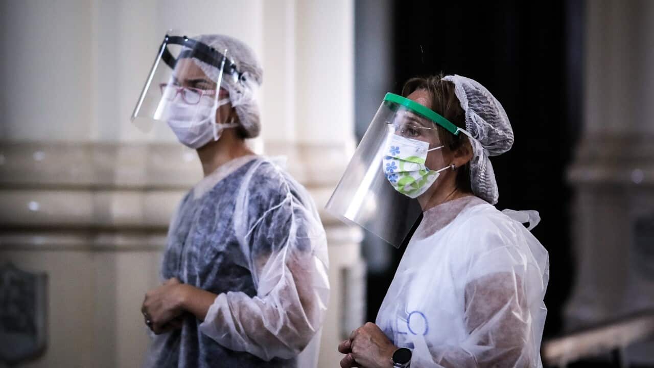 Nurses pray before applying vaccines against flu at a church in Buenos Aires, Argentina, 11 April 2020. 