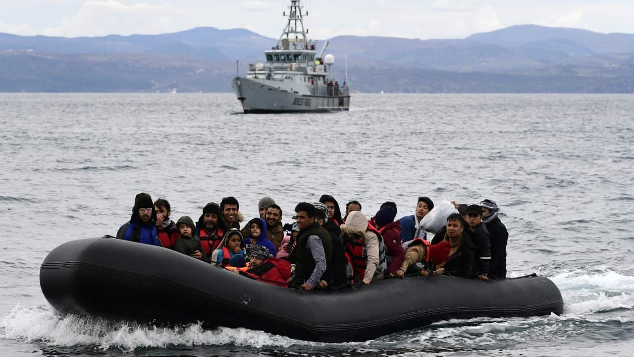 People in an inflatable boat on the water with a ship in the background
