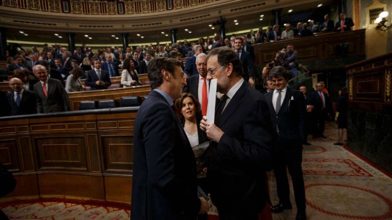 Newly re-elected Spain's Prime Minister Mariano Rajoy, right, is greeted by lawmakers after the second and final confidence vote of the investiture debate at the Spanish Parliament in Madrid, Spain, Saturday, Oct. 29, 2016.